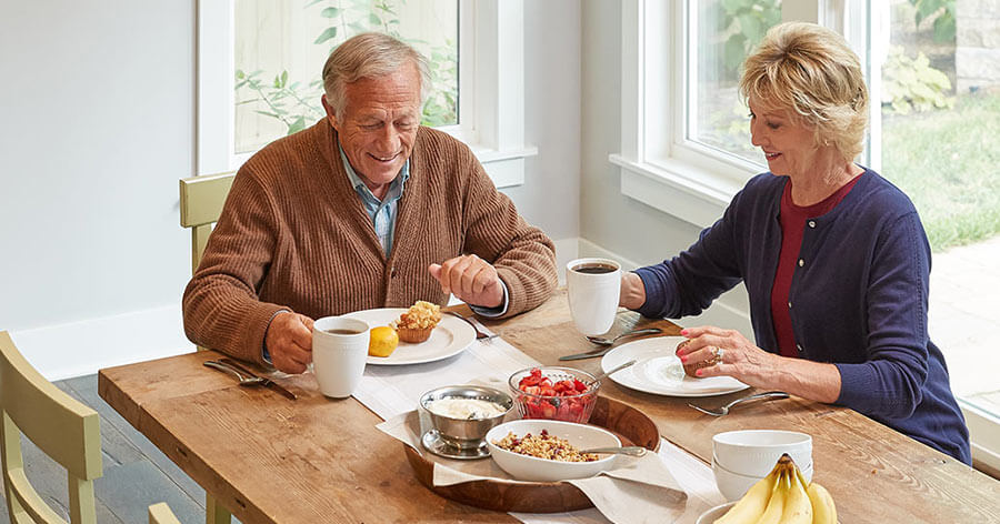 A senior couple are having breakfast in their dinning room.